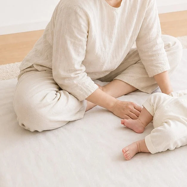 そばに座って見守る母親と、足をのばした赤ちゃん